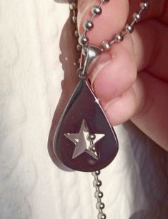 a person holding onto a silver chain with a star on the bottom and an upside down pendant attached to it