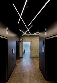 an empty room with wooden floors and black walls is lit by recessed lights above the doors