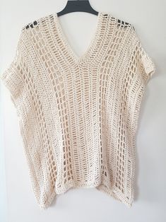 a white knitted top hanging on a hanger