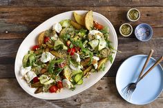 a white plate topped with a salad next to two bowls