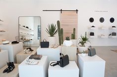 a room filled with lots of white furniture and accessories on display in front of a mirror