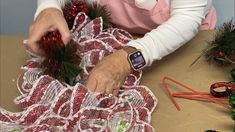 an older woman making christmas decorations on a table