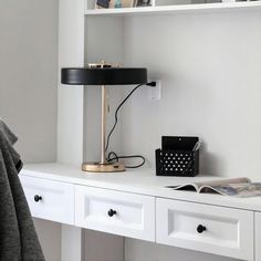 a white desk with a black lamp on it