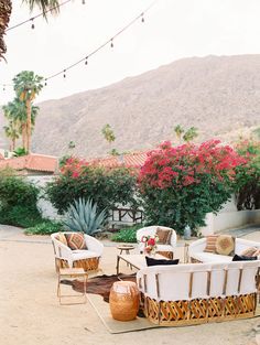 an outdoor seating area with wicker chairs and tables in front of some pink flowers