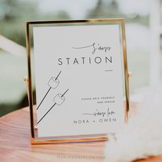 a station sign sitting on top of a wooden table next to a white fluffy ball