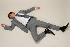 a man in a suit and tie laying on the ground with his legs spread out