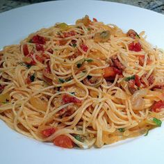 a white plate topped with pasta covered in sauce and toppings on top of a marble counter