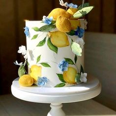 a white cake decorated with lemons and blue flowers