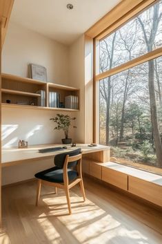 a desk and chair in front of a large window with trees outside the window sill