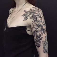 a woman wearing a black dress with flowers on her arm and chest tattooing it's upper half