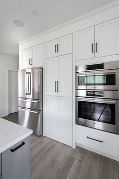 a kitchen with white cabinets and stainless steel appliances, including an oven in the center