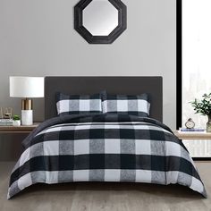 a black and white checkered comforter on a bed with a mirror above it