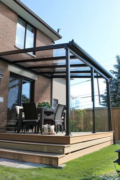 a patio covered in glass and furniture next to a brick building