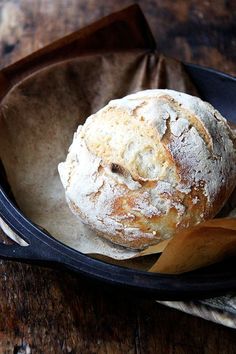 a loaf of bread sitting on top of a black plate next to a wooden spoon