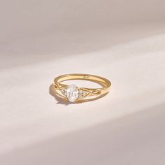 a yellow gold ring with two diamonds on the top and bottom, sitting on a white surface