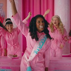 a group of women in pink pajamas standing next to each other with their arms up