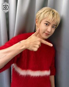 a person pointing to the side with their hand on his shoulder and wearing a red sweater