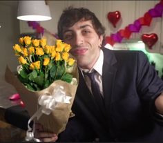 a man in a suit holding a bouquet of yellow tulips on valentine's day