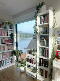 a room filled with lots of books on top of shelves next to a large window