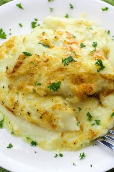 a white plate topped with mashed potatoes covered in parmesan cheese and garnished with parsley