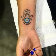 a woman's hand with a small tattoo on her wrist and an evil eye in the middle