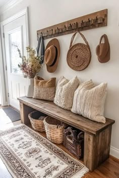 a wooden bench with hats on it next to a rug and other items hanging on the wall