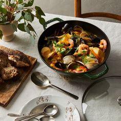 a pan filled with clams and meat on top of a table next to a cutting board