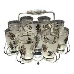 a set of twelve glass cups with metal handles and leaves on the rims are shown