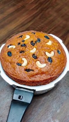 a cake with nuts and raisins on it sitting in a frying pan