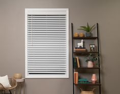 a living room filled with furniture and a window covered in white shutters next to a bookshelf