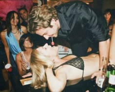 a man kissing a woman on the cheek in front of other people at a party