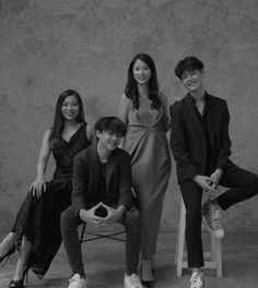 four people posing for a black and white photo with one person sitting on a chair