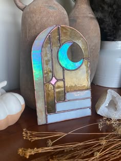 an old stained glass window sitting on top of a wooden table next to vases