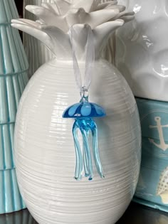 a blue glass jellyfish ornament sitting on top of a white vase