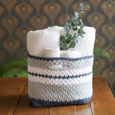 a crocheted basket with two rolls of toilet paper and a plant in it