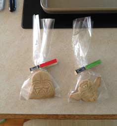 two star wars cookies in plastic bags on a counter top with pens and scissors