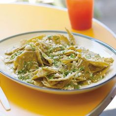 pasta with pesto and parmesan cheese in a bowl on a yellow table