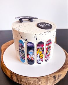 a white cake with skateboard designs on it sitting on a wooden platter next to a black and white wall