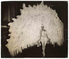 a woman standing in front of a huge pile of feathers