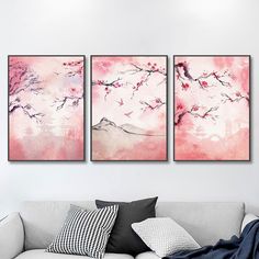 three paintings are hanging on the wall above a couch in a living room with pillows