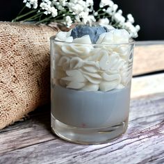 a glass vase filled with white flowers on top of a wooden table next to a burlick bag