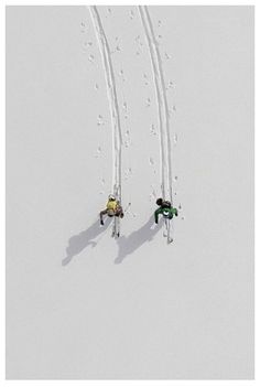 two skiers are skiing down a snowy hill together with ski poles in the air