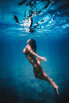 a man swimming in the ocean with his arms out and feet up above water's surface