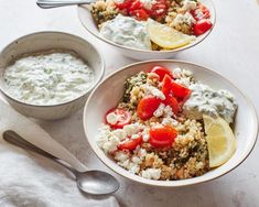 two bowls filled with food next to a bowl of yogurt and lemon wedges