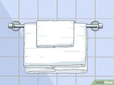 a white towel hanging on the wall above a toilet paper dispenser in a tiled bathroom