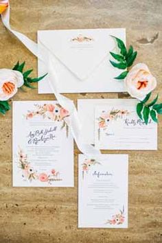 the wedding stationery is laid out with flowers and greenery, along with an envelope