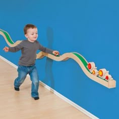 a young boy playing with a wooden toy train set in a playroom at pinterest