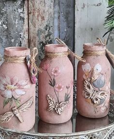 three pink vases with flowers painted on them