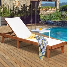 an empty chaise lounge next to a swimming pool with umbrella and towel on it