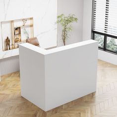 a white reception table with a plant in the corner on top of it, next to a window